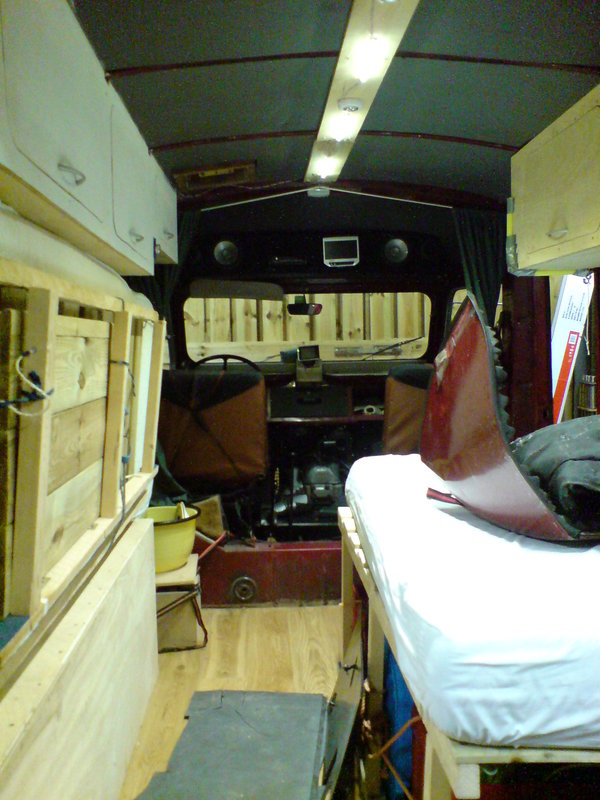 Zo staat ie er meestal bij: bed aan de deur kant neergeklapt, daaronder kratten met campingspullen (en hier motorkap-opberg-plaats). Zie ook de LEDlampjes, ze zijn dimbaar. En natuurlijk het massief eikenhouten parket.